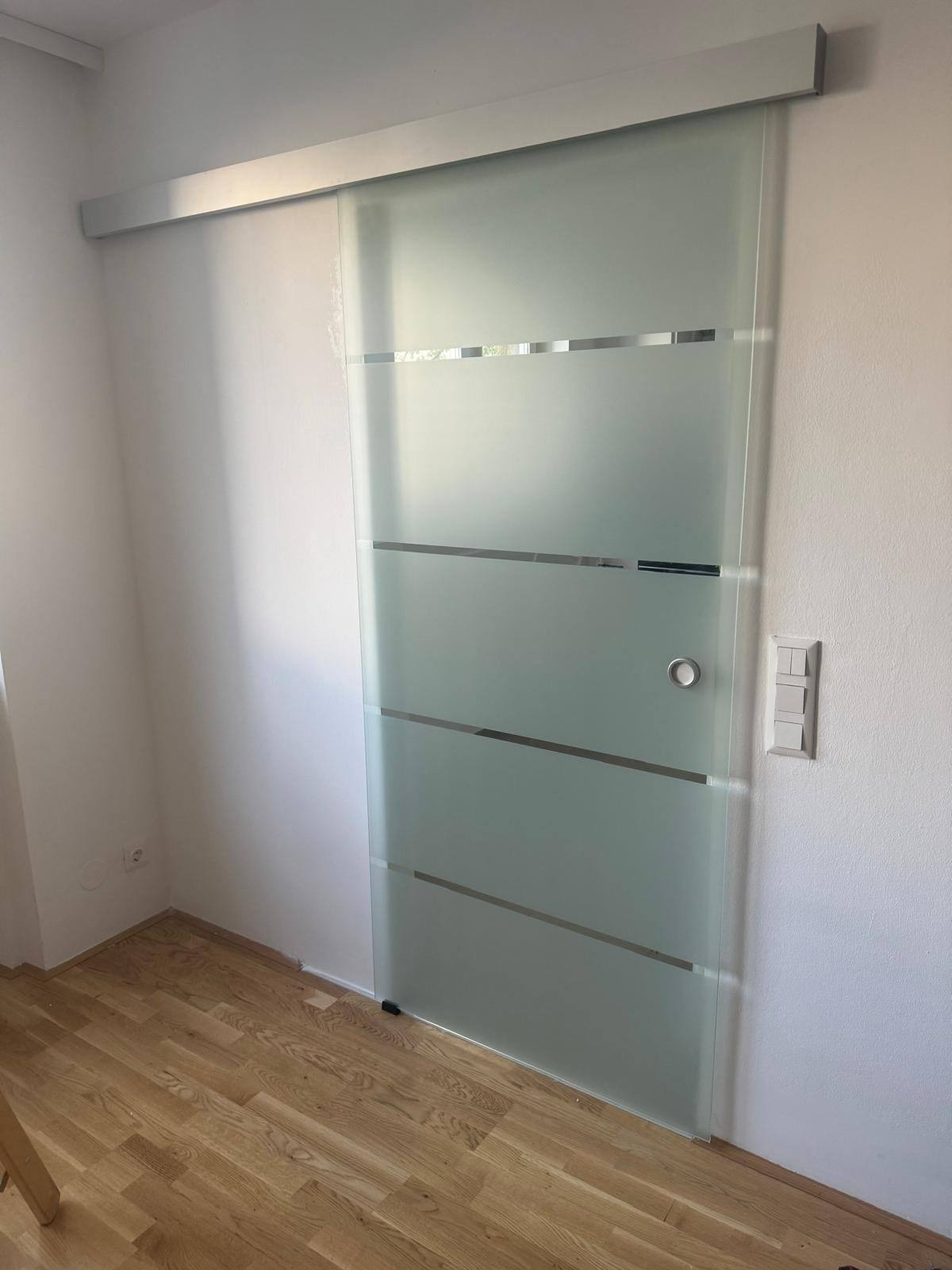 Glas-Schiebetür mit horizontalen Streifenätzungen als Raumtrenner in einer Wohnung in 1080 Wien Josefstadt